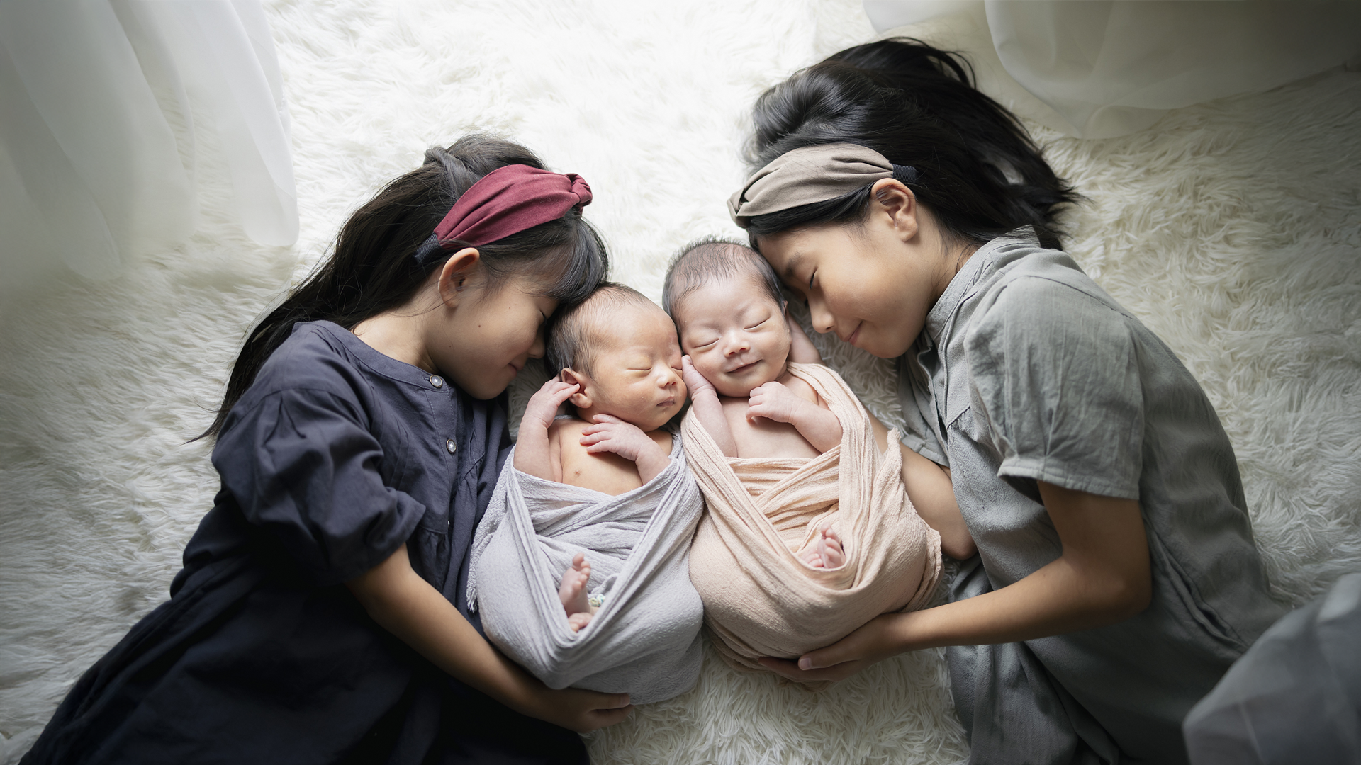 双子のニューボーンフォト。双子の赤ちゃんと二人のお姉ちゃんのきょうだい写真、自然光が差し込むフォトスタジオ