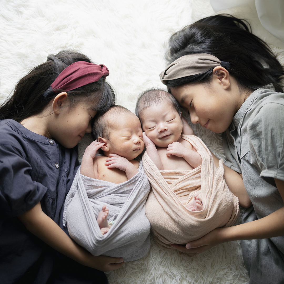 双子のニューボーンフォト。双子の赤ちゃんと二人のお姉ちゃんのきょうだい写真、自然光が差し込むフォトスタジオ