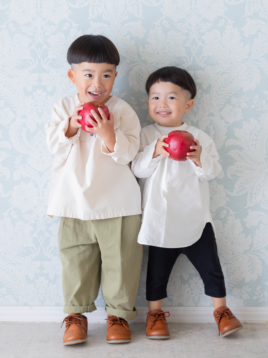 りんごを持って楽しそうに笑う男の子2人兄弟の家族写真