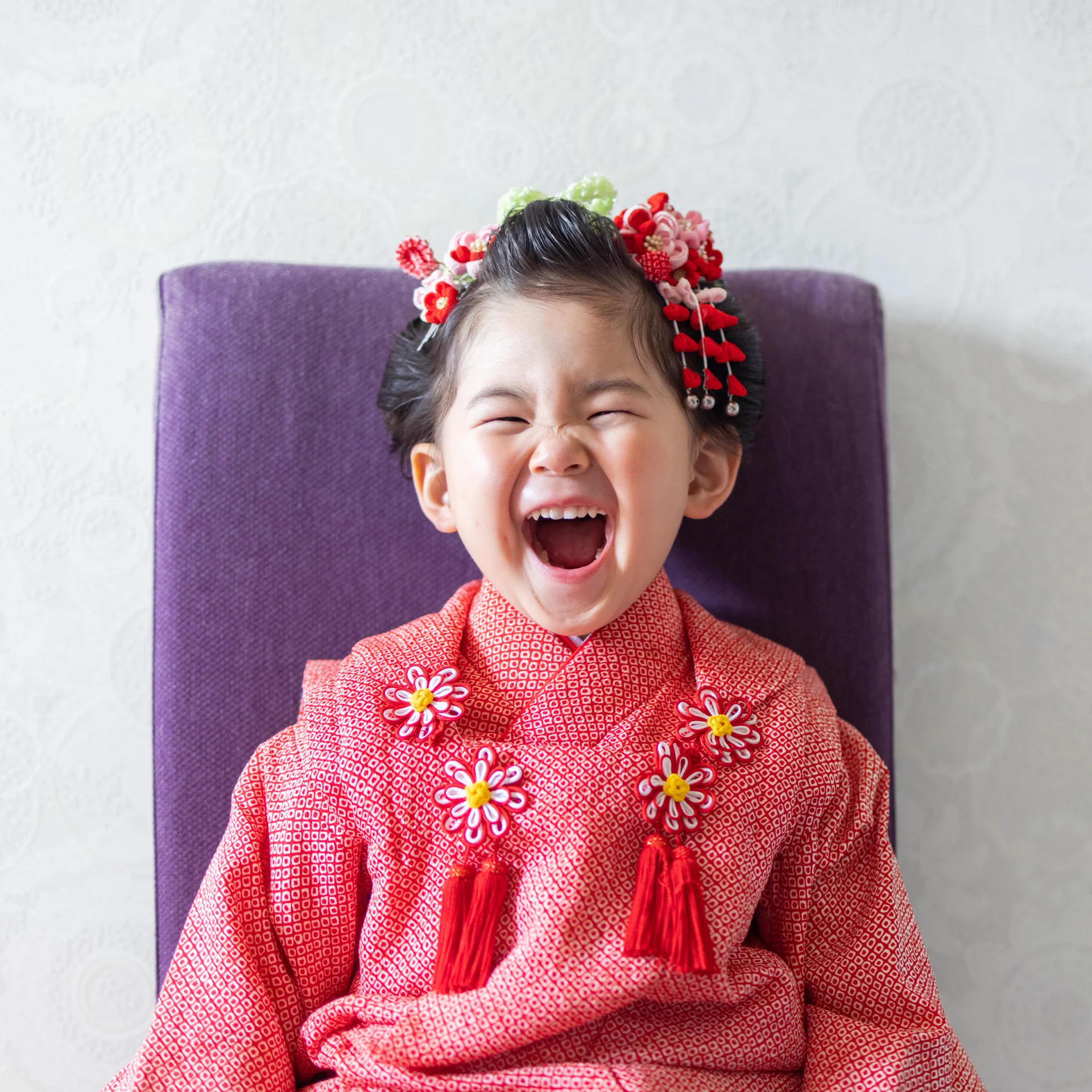 日本髪とモダンな赤い着物で笑顔を見せる3歳女児の七五三スタジオ写真